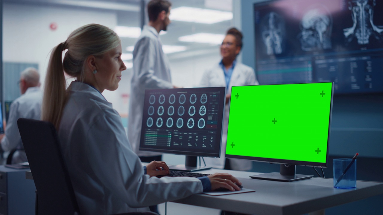 医院研究实验室:女性医学生物技术科学家工作在绿屏色度键计算机与脑扫描MRI图像。背景:神经科学家开会分析核磁共振扫描视频下载