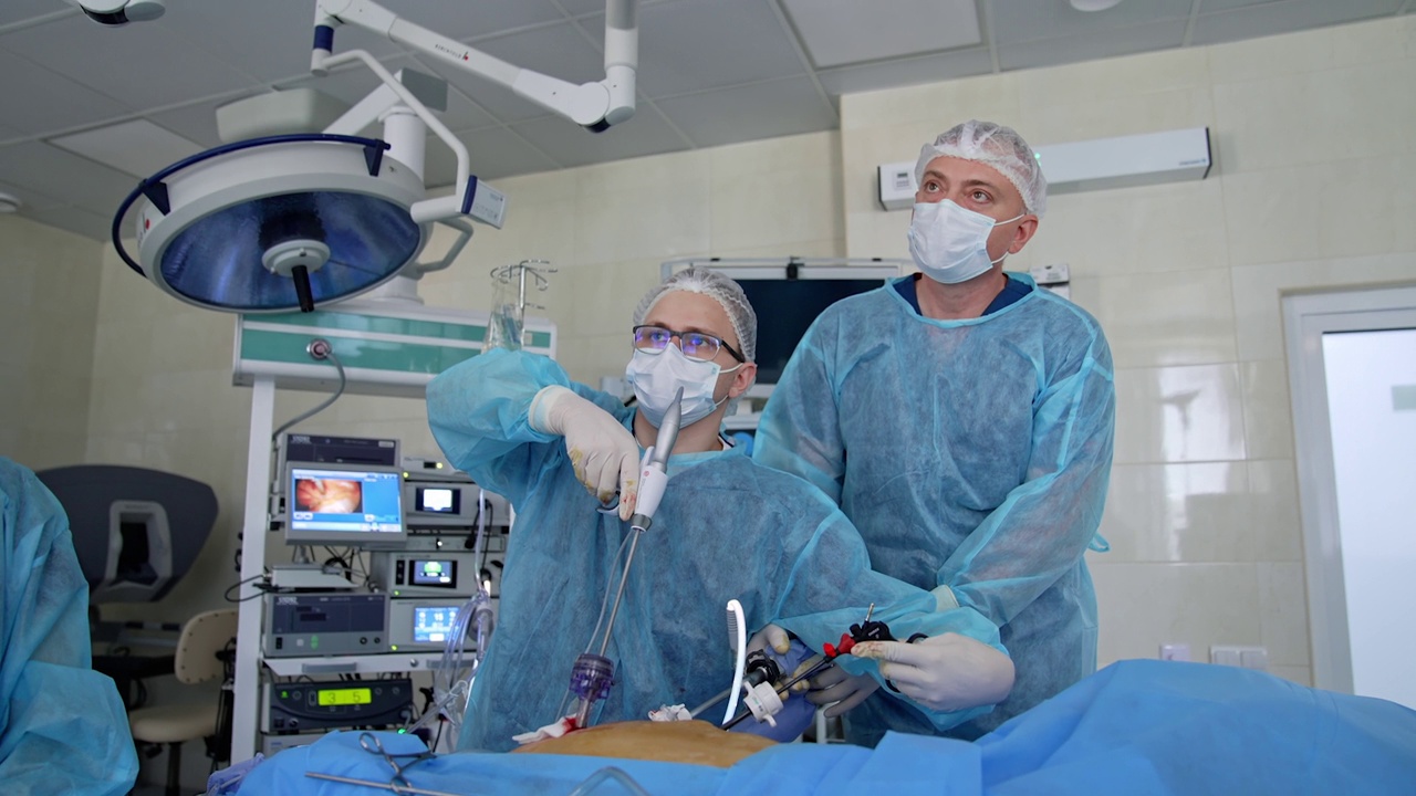 两个医生在重症监护室看着监视器。一群外科医生带着手术设备在手术室里视频下载