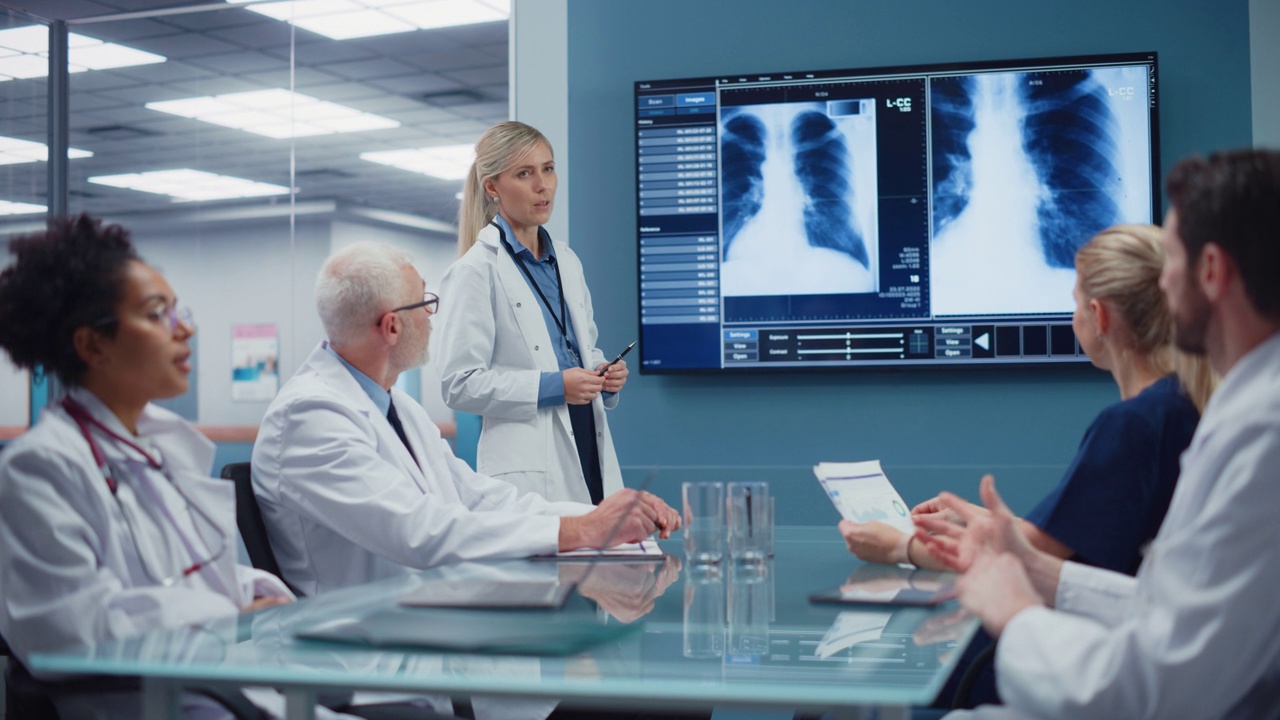 医院会议室:女医生在电视屏幕上展示病人的x光片，医生小组讨论病人的治疗。研究科学家谈论治疗，药物，医学发展视频下载