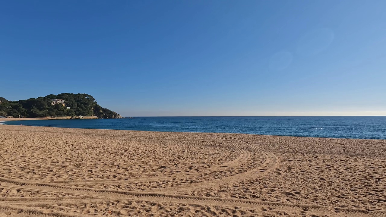 平静的海洋景观，沙滩上的轮胎痕迹和清澈的蓝天视频素材
