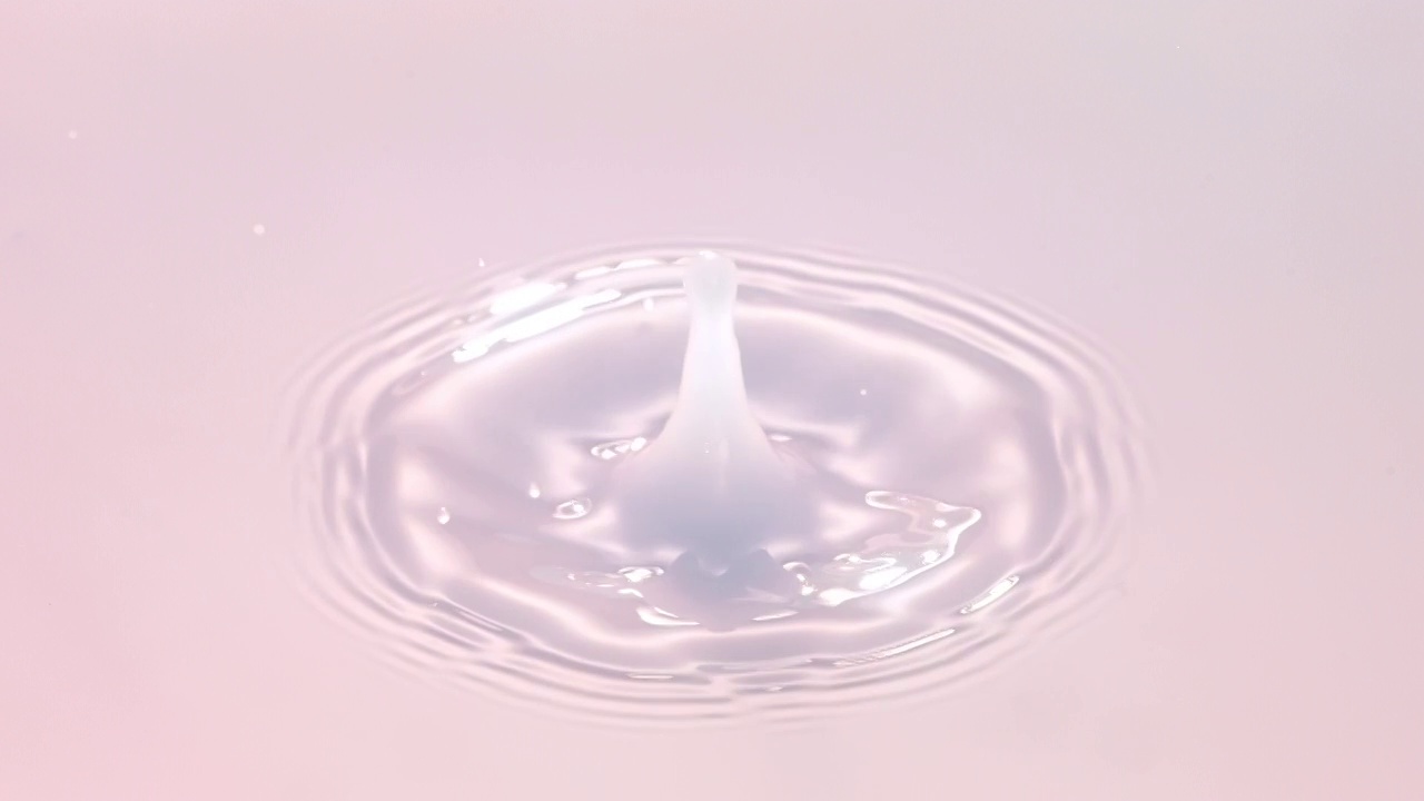特写镜头和超慢动作与头顶的视角，一个乳白色的水滴落入浅粉色半透明的液体池，并产生涟漪视频下载