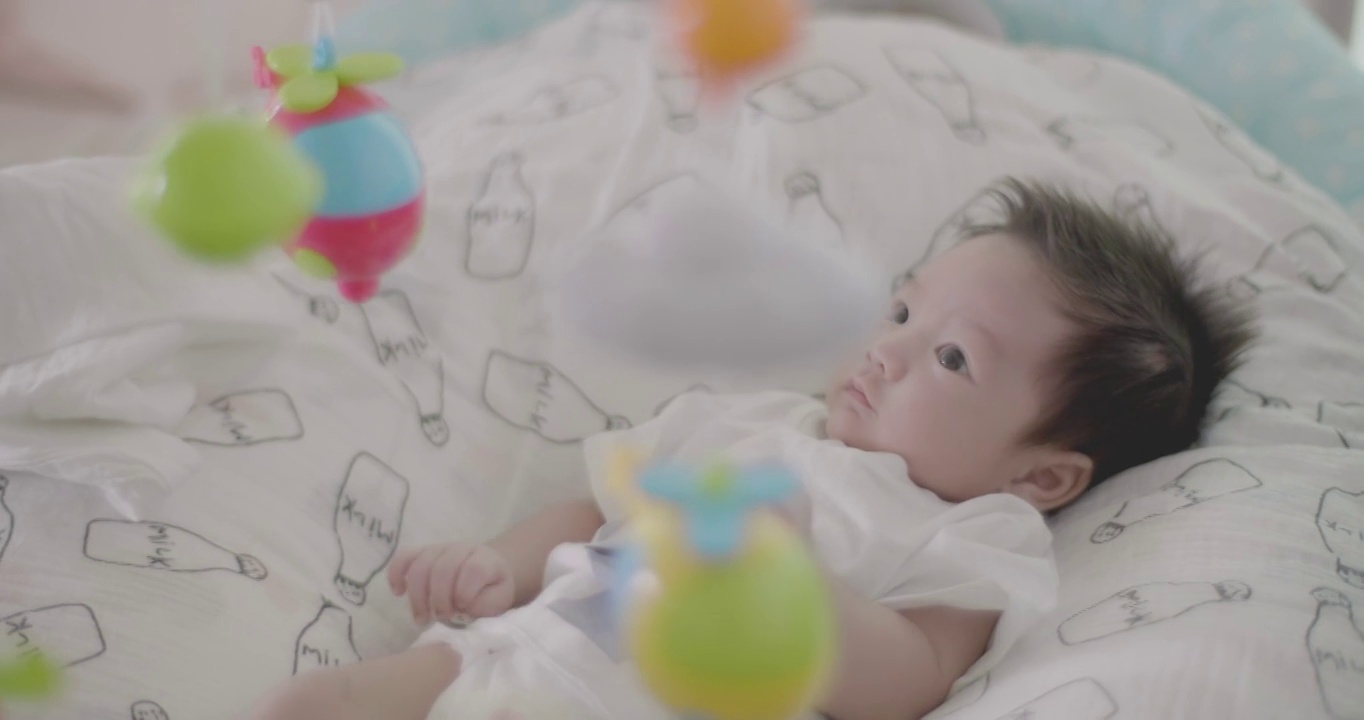可爱的亚洲宝宝在床上玩挂手机。视频下载