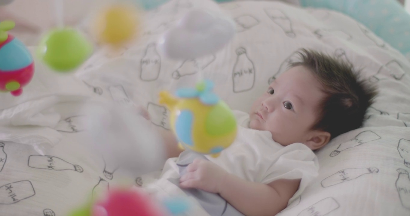 可爱的亚洲宝宝在床上玩挂手机。视频素材