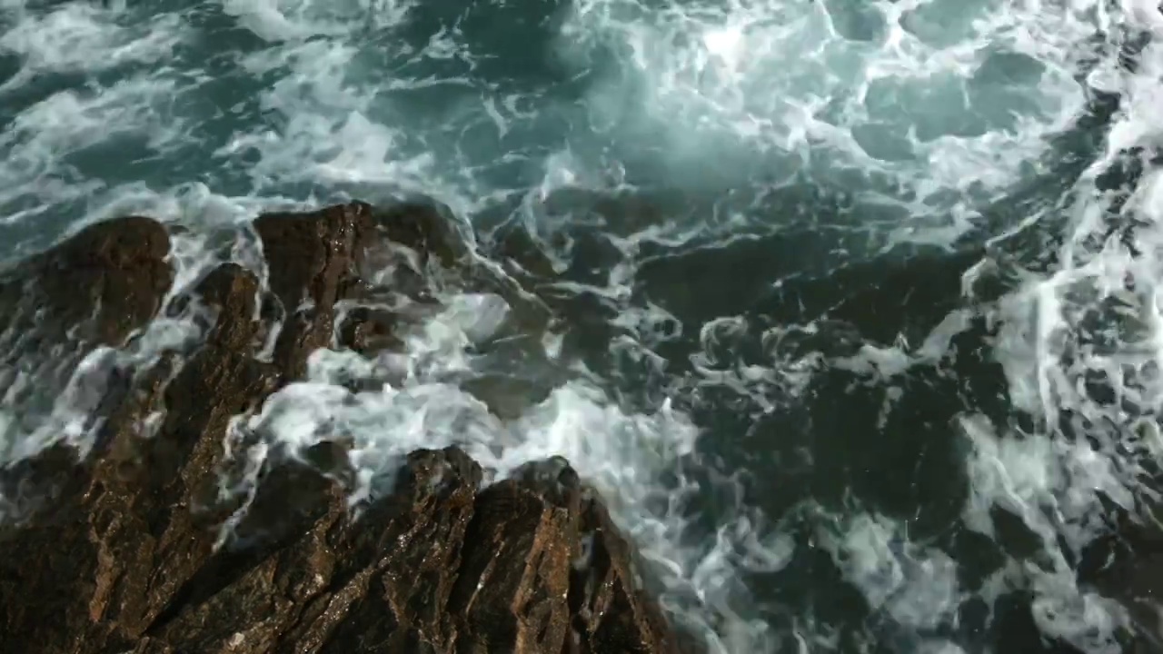 从高处俯瞰蔚蓝的大海。有创造力。巨浪拍打着巨石视频素材
