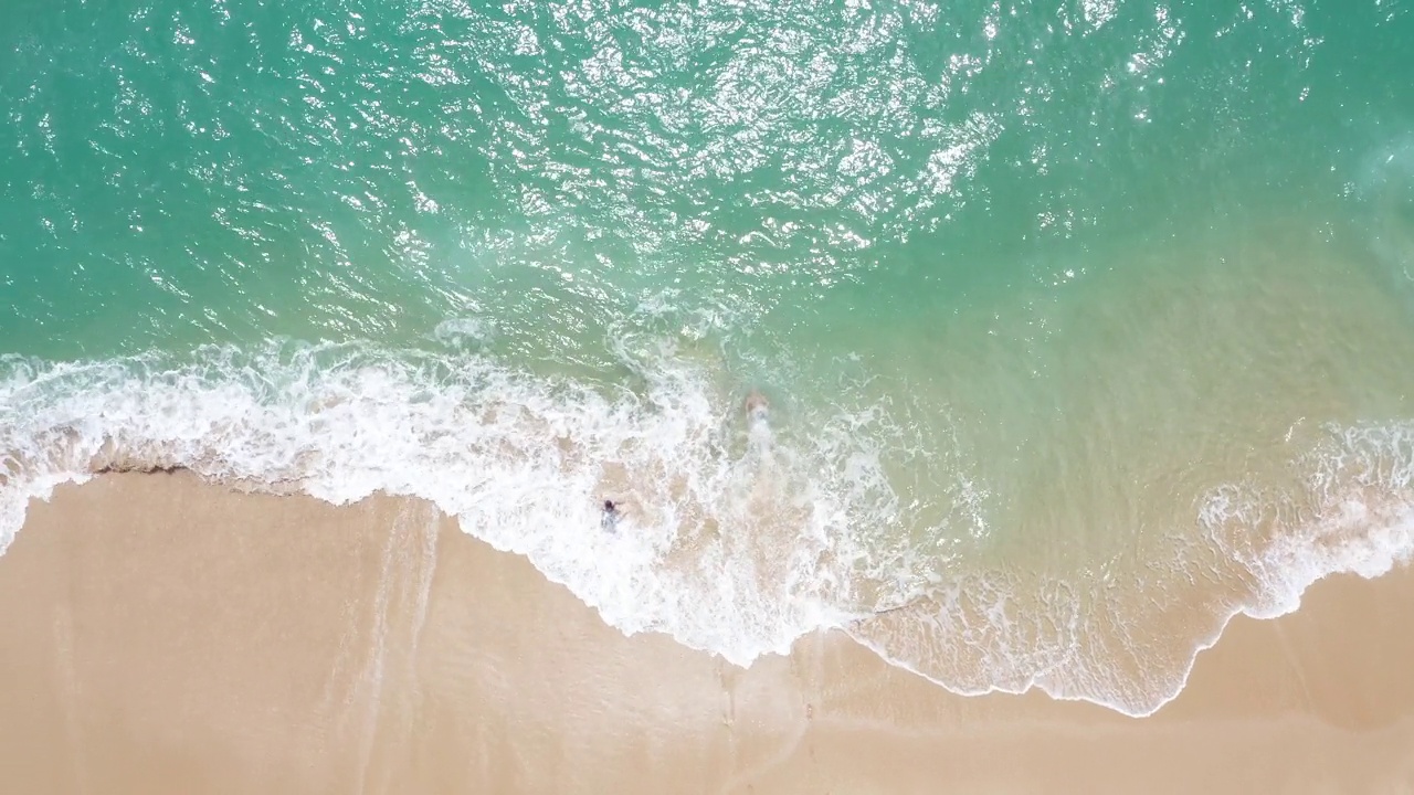 幸福的情侣在完美的沙滩上奔向印度洋的海浪，一起享受游泳的乐趣。在斯里兰卡坦加勒附近，无人机拍摄了4K镜头。视频素材