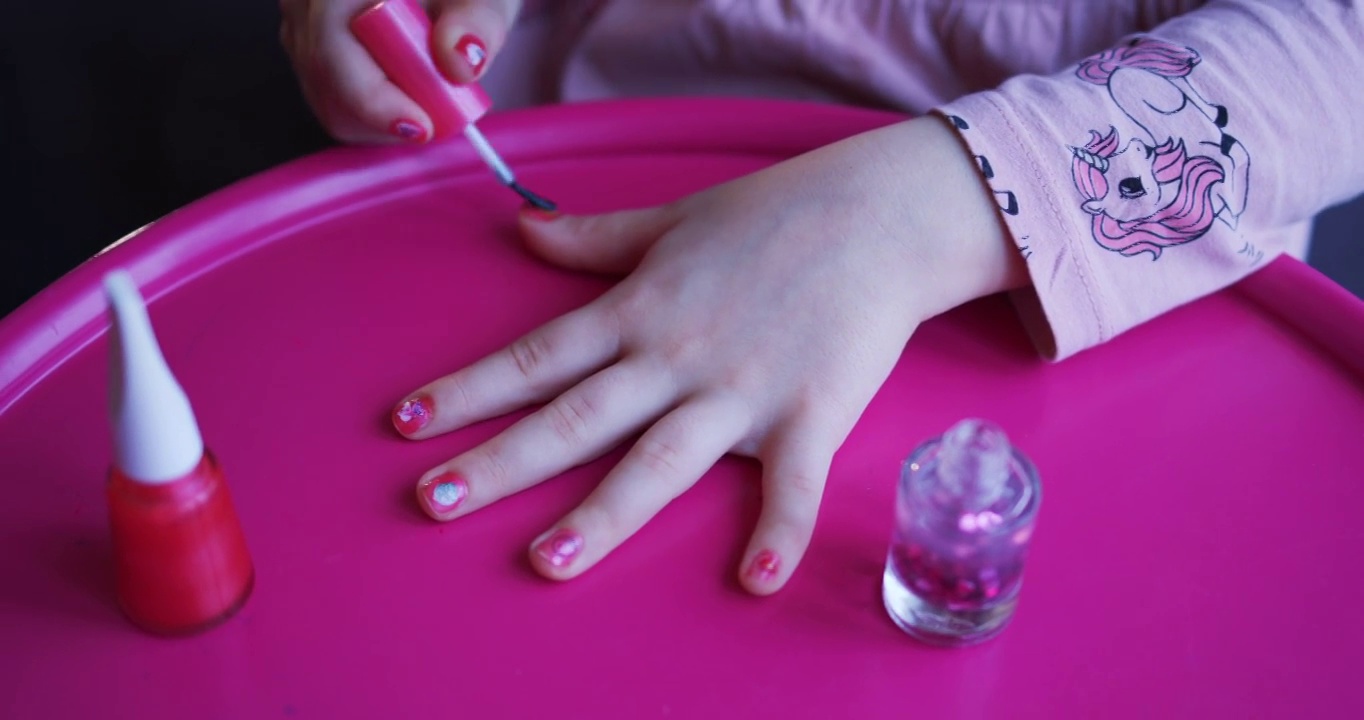 美丽的卷发小女孩用儿童指甲油涂指甲视频下载