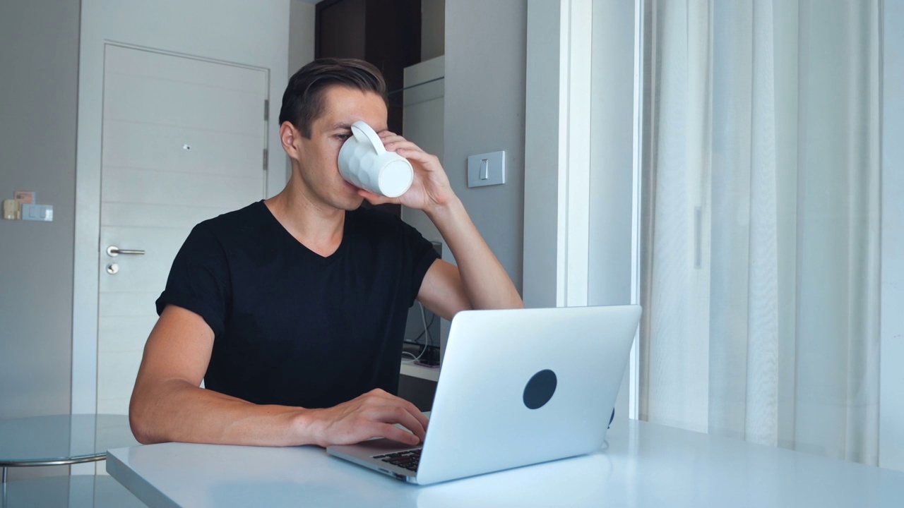 年轻的男性自由职业者用笔记本电脑处理图像，在家喝咖啡。视频素材