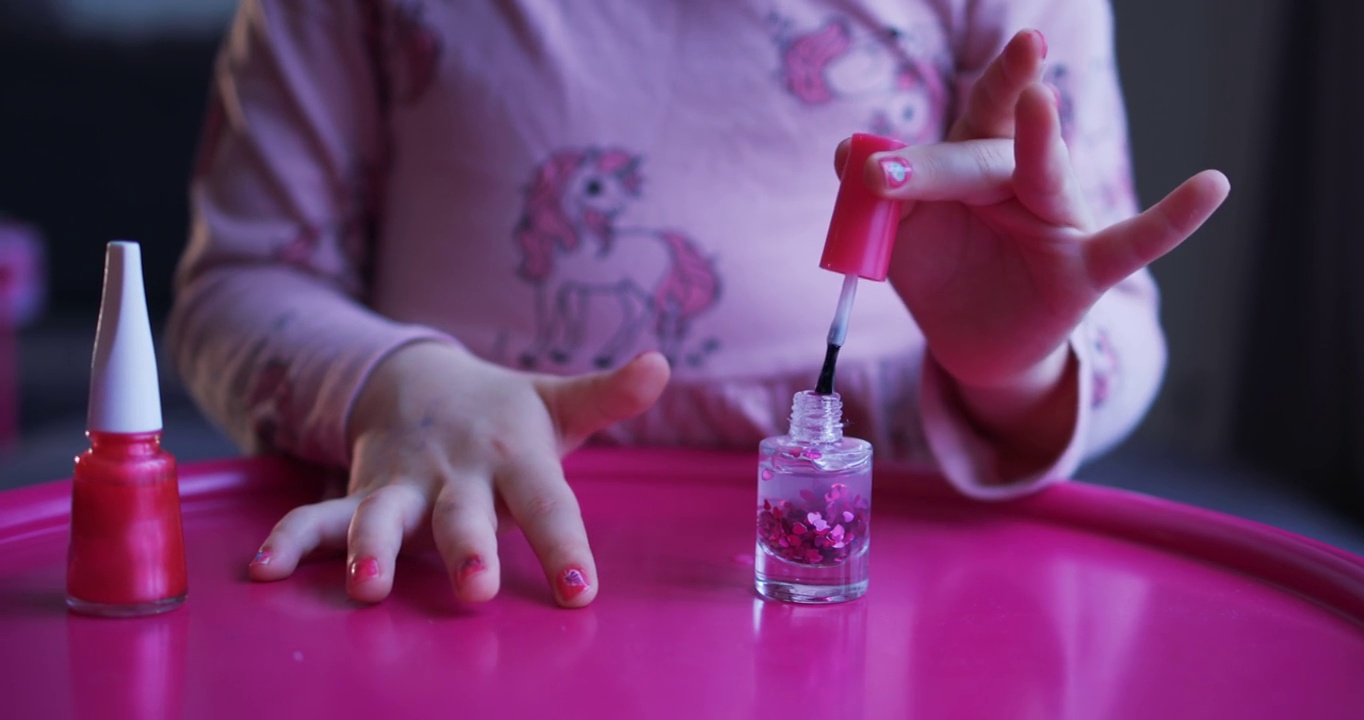 美丽的卷发小女孩用儿童指甲油涂指甲视频下载
