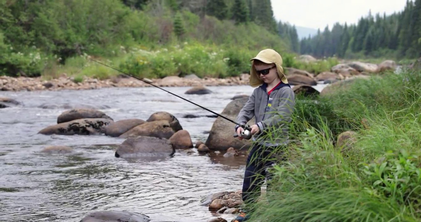 可爱的红发男孩在魁北克的河里钓鱼视频素材