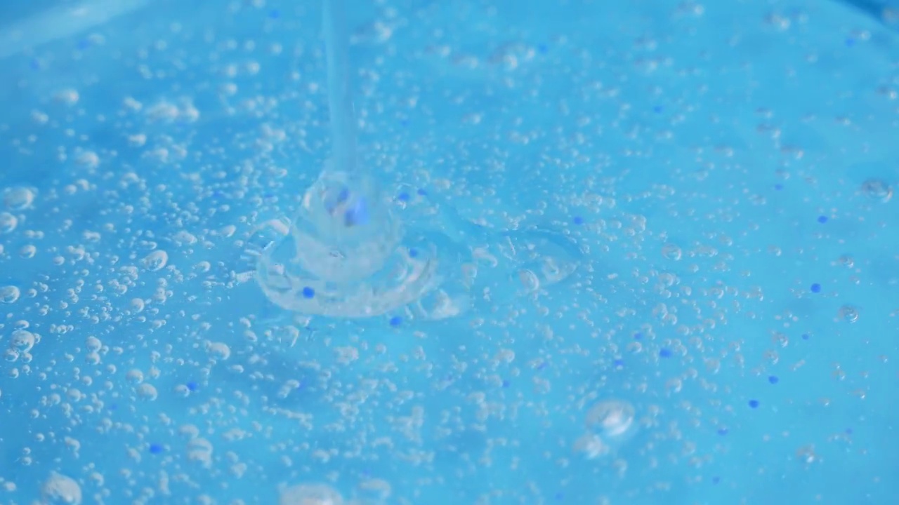 一股带着小气泡的透明化妆品凝胶滴落在蓝色的表面。精华液、抗衰老霜、洗发露、抗菌凝胶、透明质酸视频素材