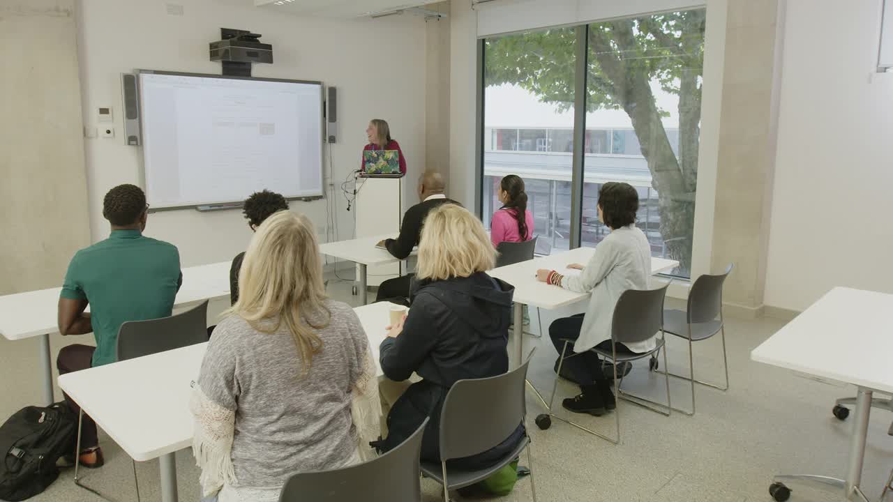 成熟的学生在教室的讲台上听女老师讲课视频下载