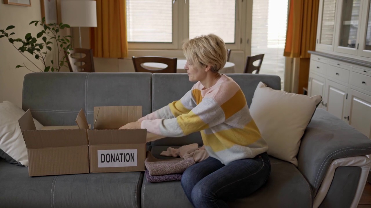 一位女士正在包装衣服，准备捐给当地的慈善机构视频素材