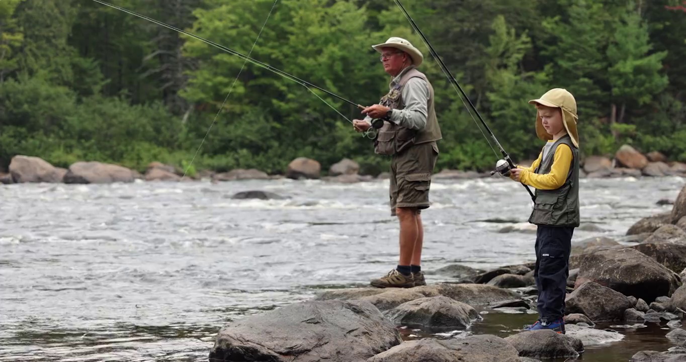可爱的红发男孩和爷爷在魁北克的河中钓鱼视频素材