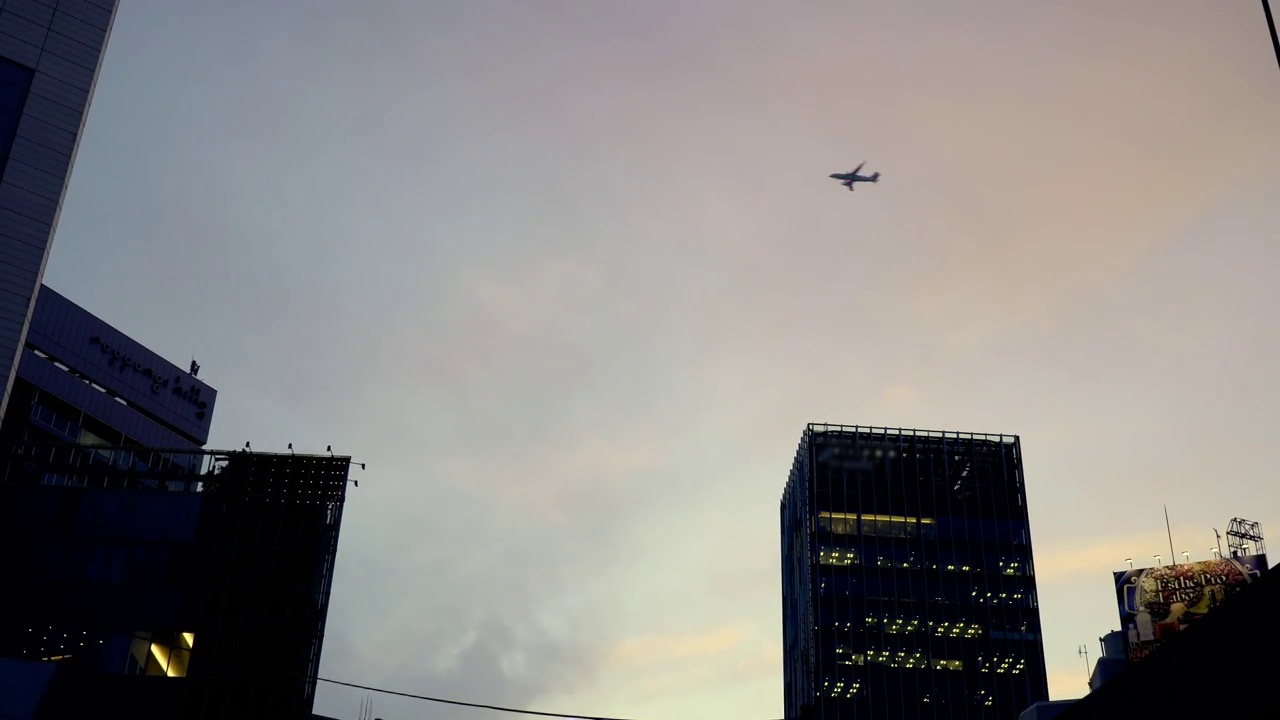 飞机在黄昏时分飞过城市的天空。东京六本木的都市风光视频素材