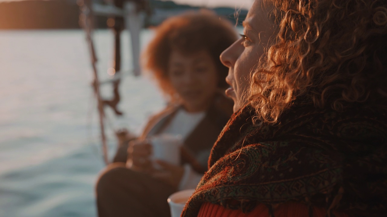 黄昏时分，两个女人在帆船的甲板上喝咖啡视频素材