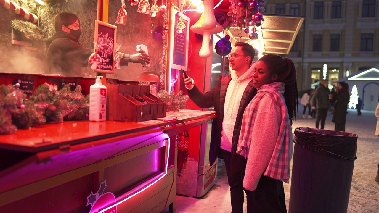一对情侣在圣诞市场上的小摊上买饮料视频下载