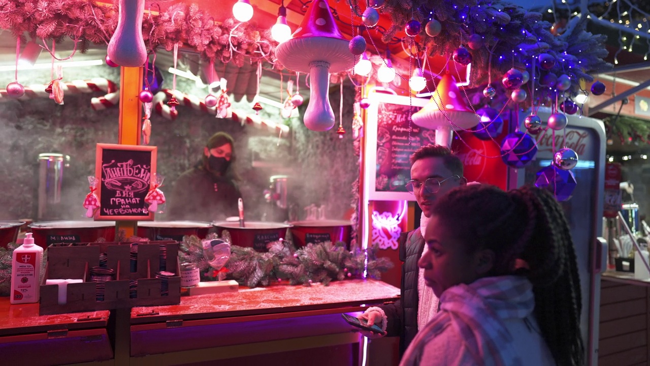 一对夫妇在圣诞市场的摊位上买饮料视频下载