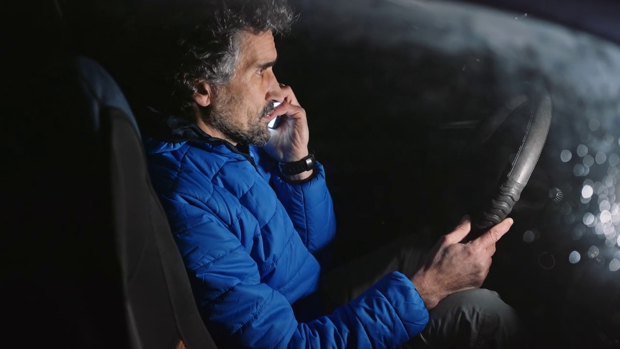 男人晚上在车里用手机浏览社交媒体。视频下载