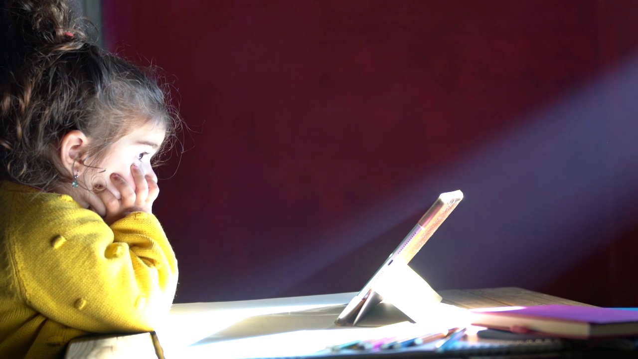 学龄前女孩在光束下使用数码平板电脑的4K视频视频下载