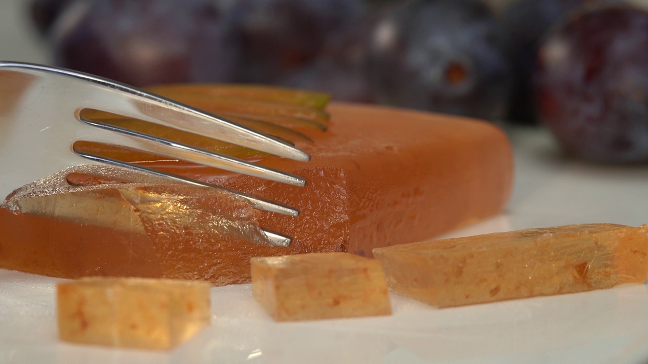 特写叉断一块橘子酱的背景上成熟的李子。土耳其软糖。水果甜点，甜，枣。视频下载