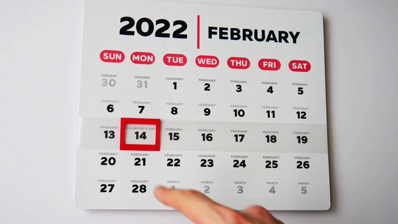 墙上挂历2022年2月的美丽页面和一只男性手将红色光标移动到情人节日期视频素材