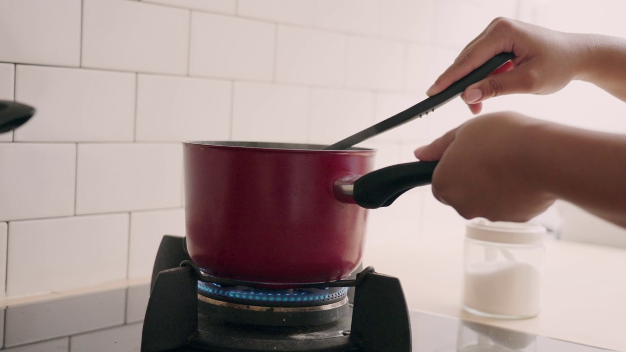 一个女人在厨房里做饭，在锅里搅拌酱汁视频素材