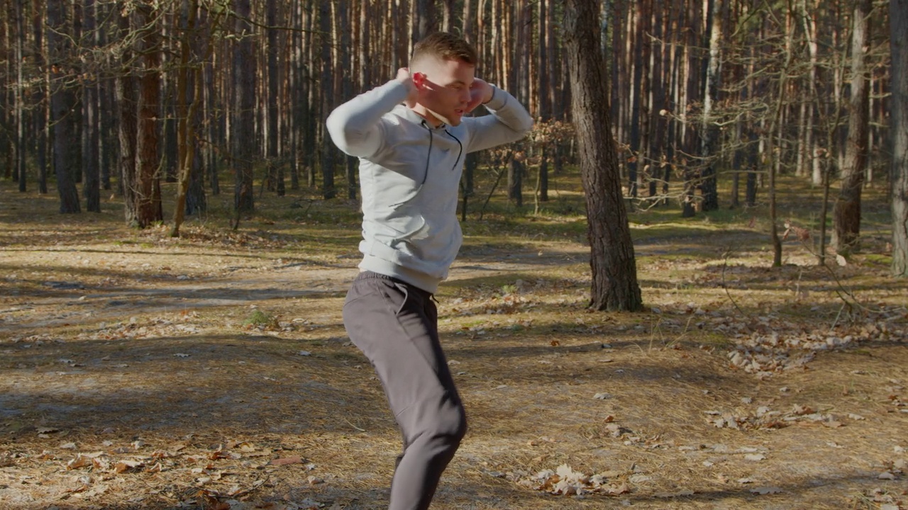 一个年轻人在森林里热身，准备晨练视频下载