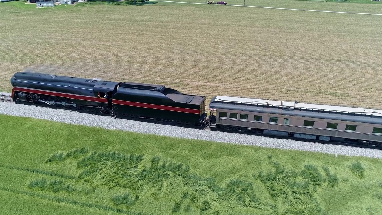 在一个阳光明媚的日子里，一辆古董蒸汽客运火车在农田里穿行视频素材