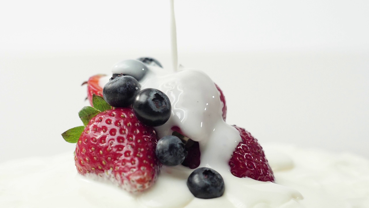 新鲜健康的食物。草莓和蓝莓和酸奶。酸奶和鲜奶油里的浆果会变色。鲜果配鲜奶油。有机浆果，清洁饮食，素食理念视频素材