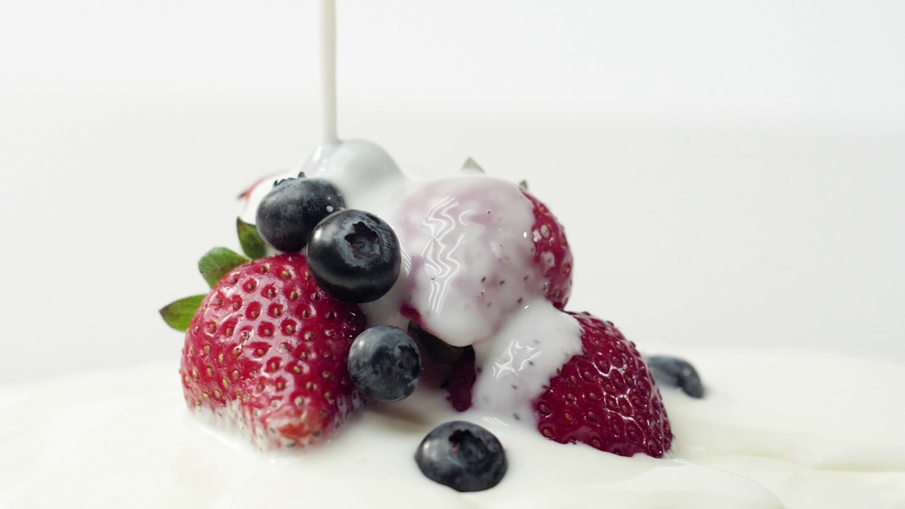 新鲜健康的食物。草莓和蓝莓和酸奶。酸奶和鲜奶油里的浆果会变色。鲜果配鲜奶油。有机浆果，清洁饮食，素食理念视频素材