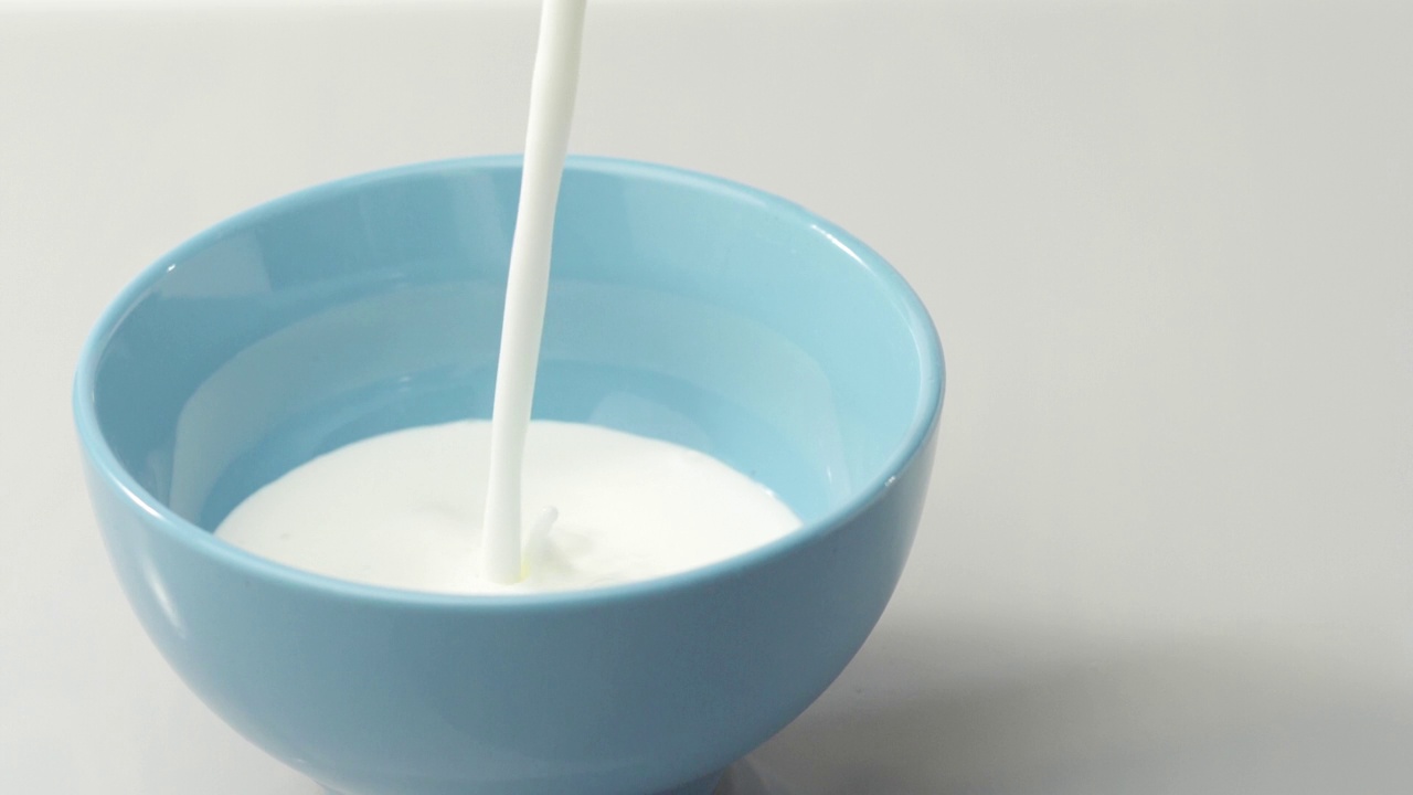 新鲜健康的食物。酸奶被倒进蓝色的碗里。鲜果配鲜奶油。有机浆果，清洁饮食，素食理念。慢动作视频素材
