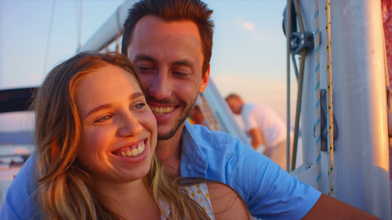 一对年轻的夫妇在游艇上欣赏日落视频素材