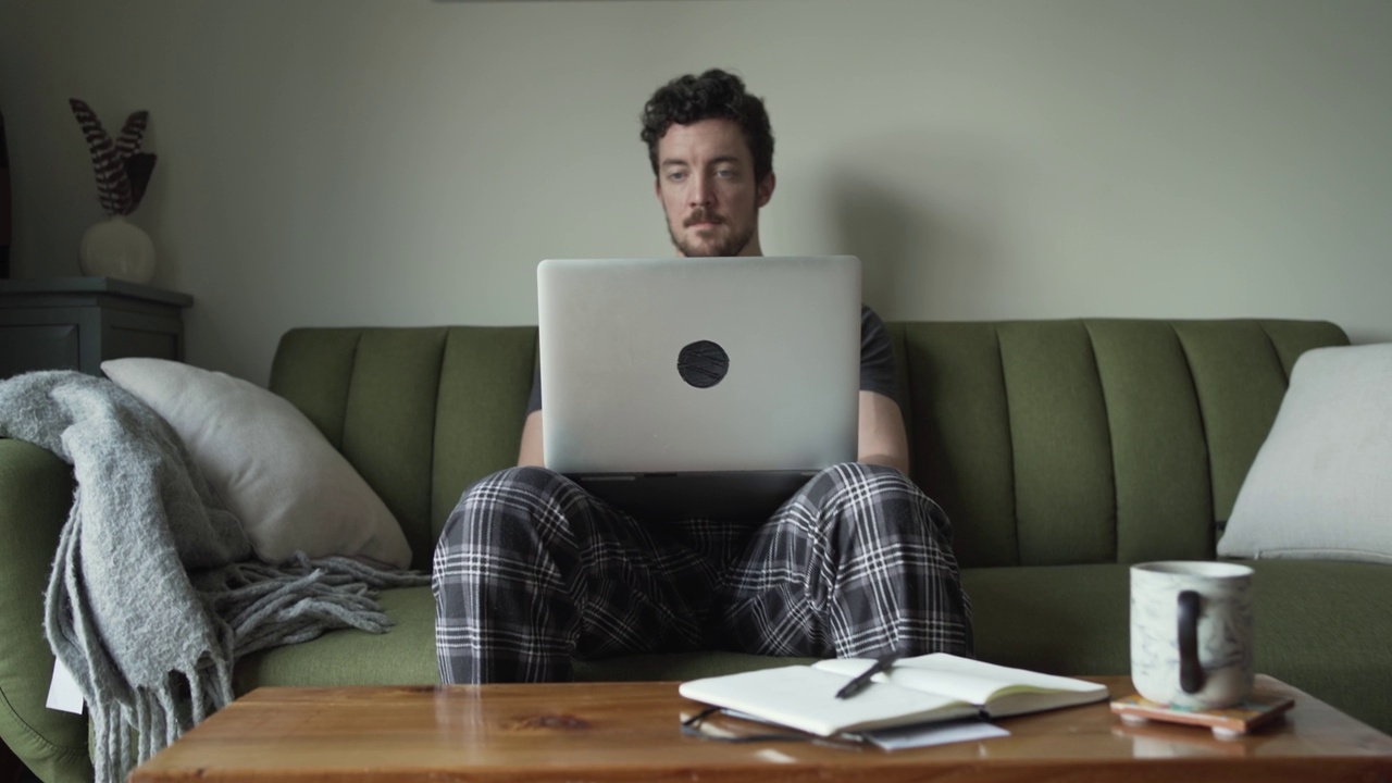 一个年轻人早上在客厅里用笔记本电脑工作视频素材