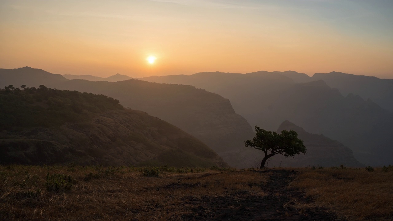 在印度马哈拉施特拉邦的雷林高原附近，Sahyadri山脉的高脊和一棵孤独的树上的日出延时拍摄视频下载