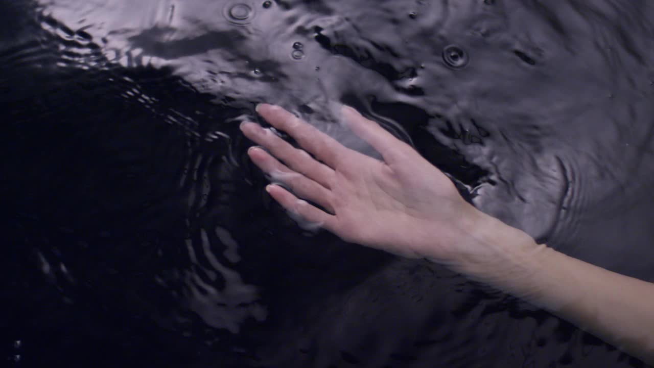 光滑如丝的水面。女性用手轻轻泼洒并触摸液体视频素材