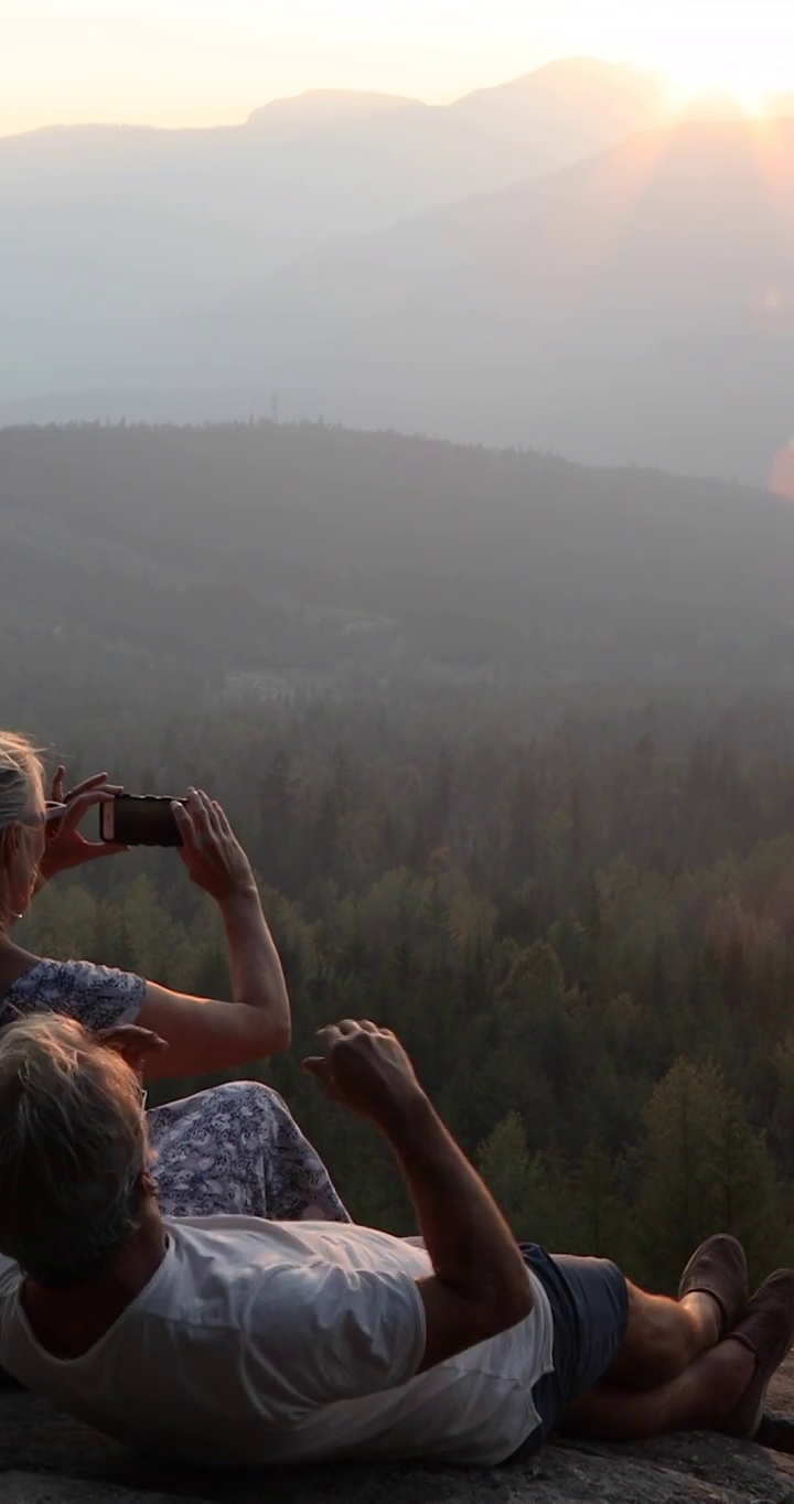 一对情侣在悬崖边观看日出，下面是森林视频素材