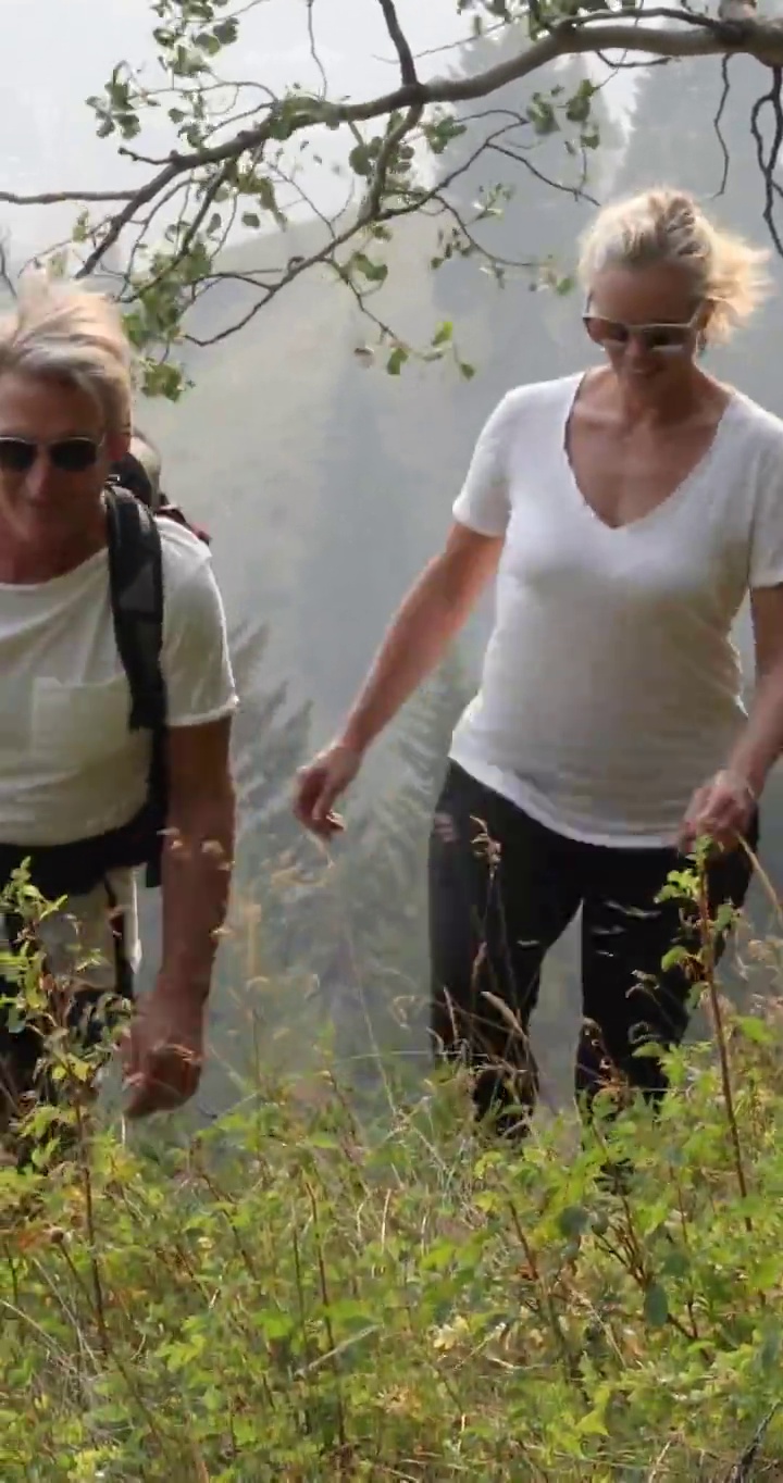 一对夫妇沿着森林覆盖的山坡走着视频素材