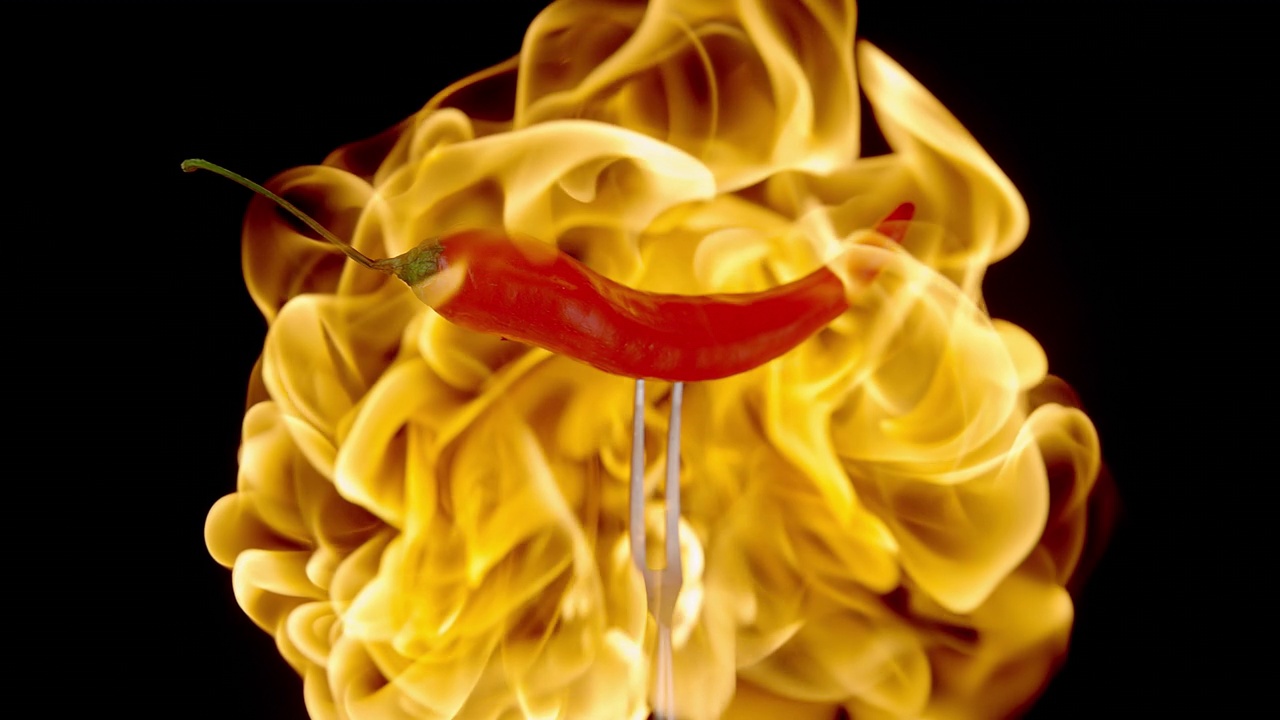 叉子上的辣椒在火焰中旋转的慢镜头视频素材