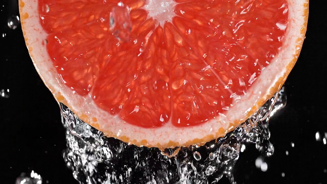 葡萄柚片(背光)被水从上面溅起，慢动作视频素材