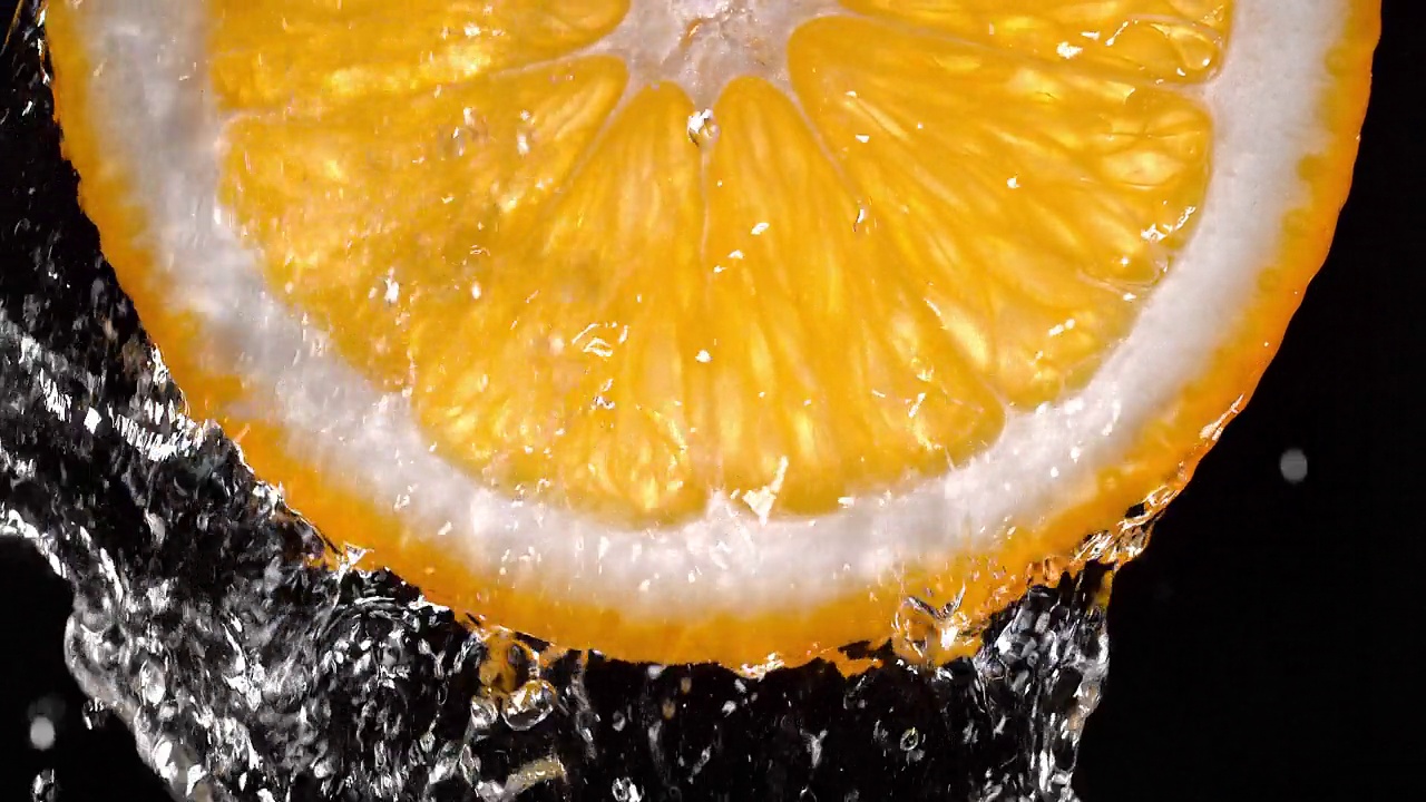 橙色切片(背光)从顶部的水溅到慢动作视频素材