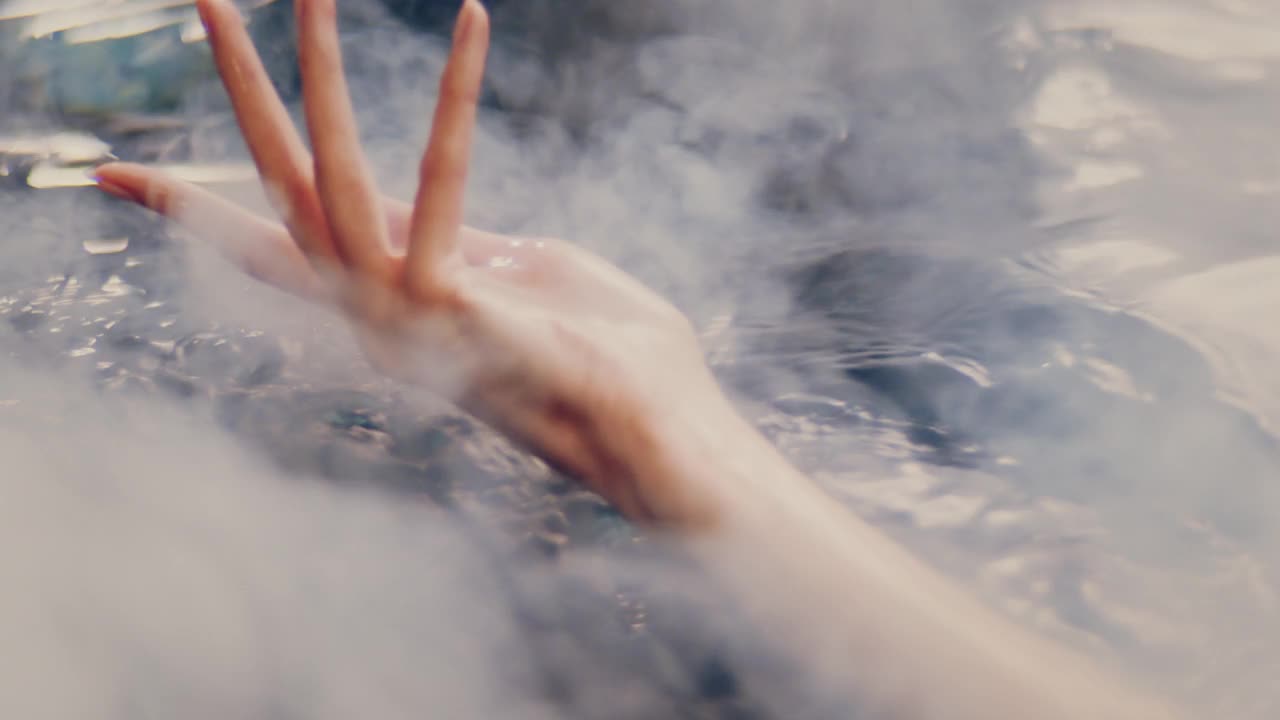 烟雾和光滑的水面。女性用手轻轻泼洒并触摸液体视频下载