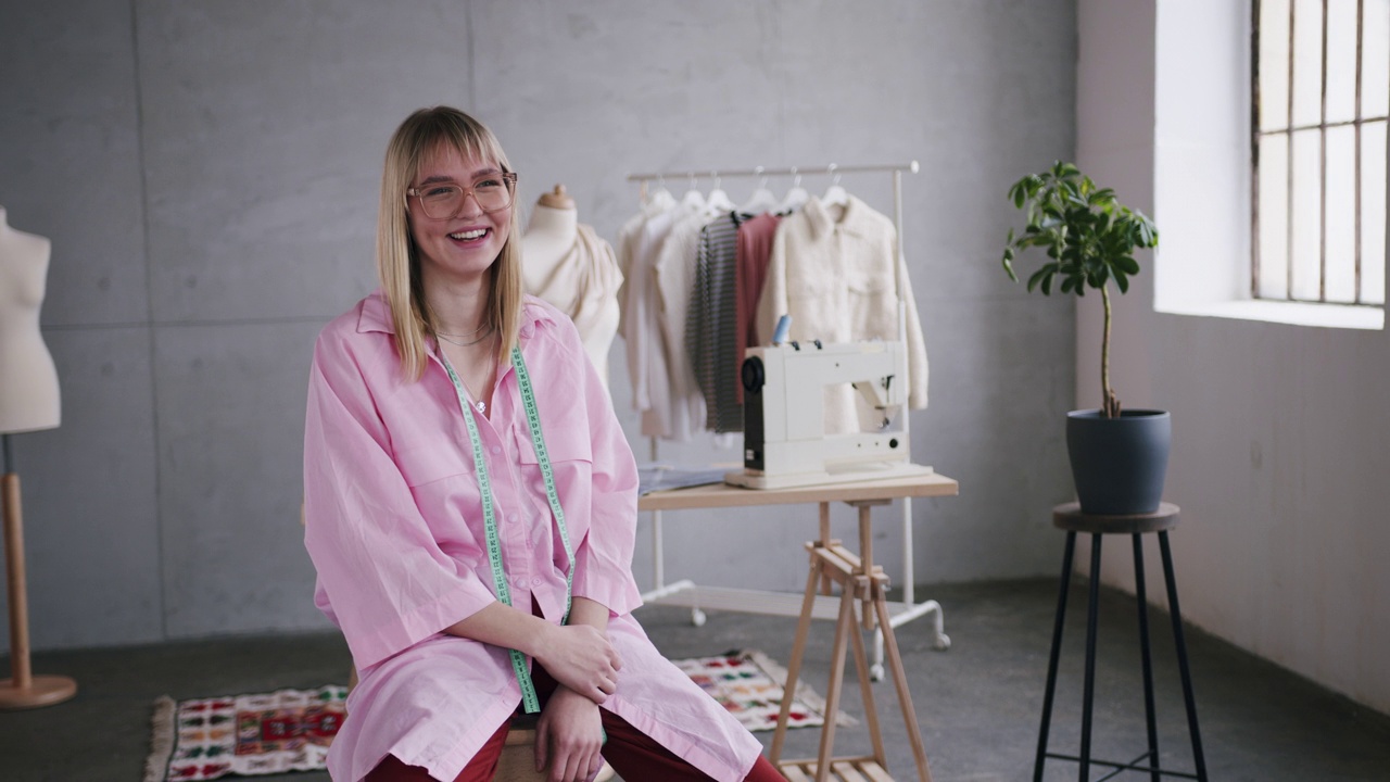 一个快乐的白人女人坐在她的时装工作室里的肖像视频下载