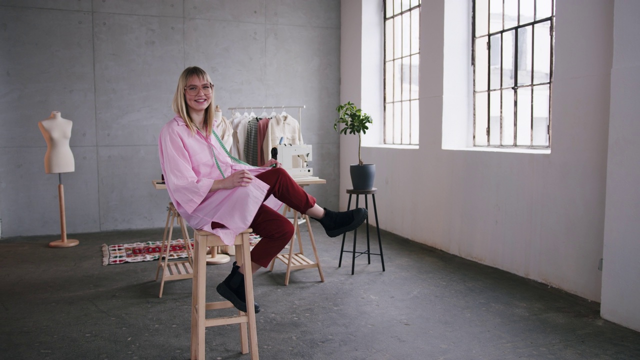 一个快乐的白人女人坐在她的时装工作室里的肖像视频下载