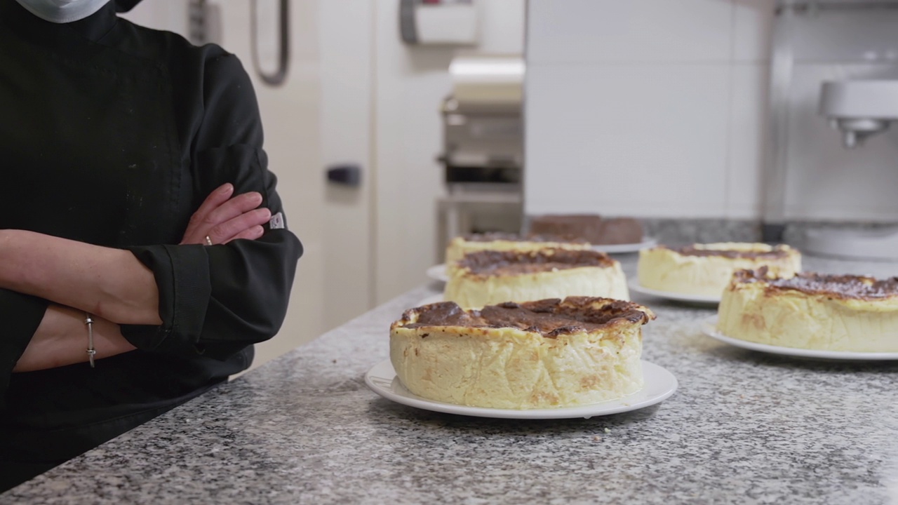 一个认不出来的糕点厨师在糖果店的奶酪蛋糕附近摆姿势的特写。高质量的FullHD镜头视频素材