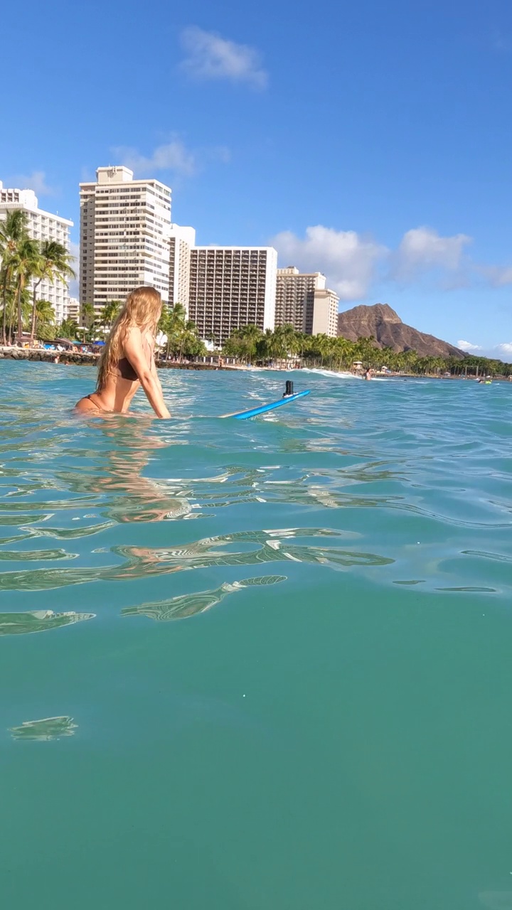 在夏威夷瓦胡岛的怀基基，一名女子坐在钻石岬附近的冲浪板上。- - - - - -垂直格式视频素材