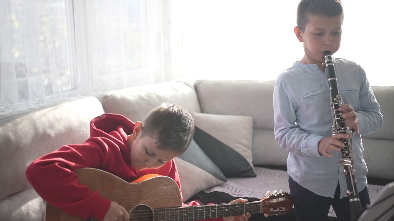 两个男孩在家里用吉他和单簧管练习音乐视频下载