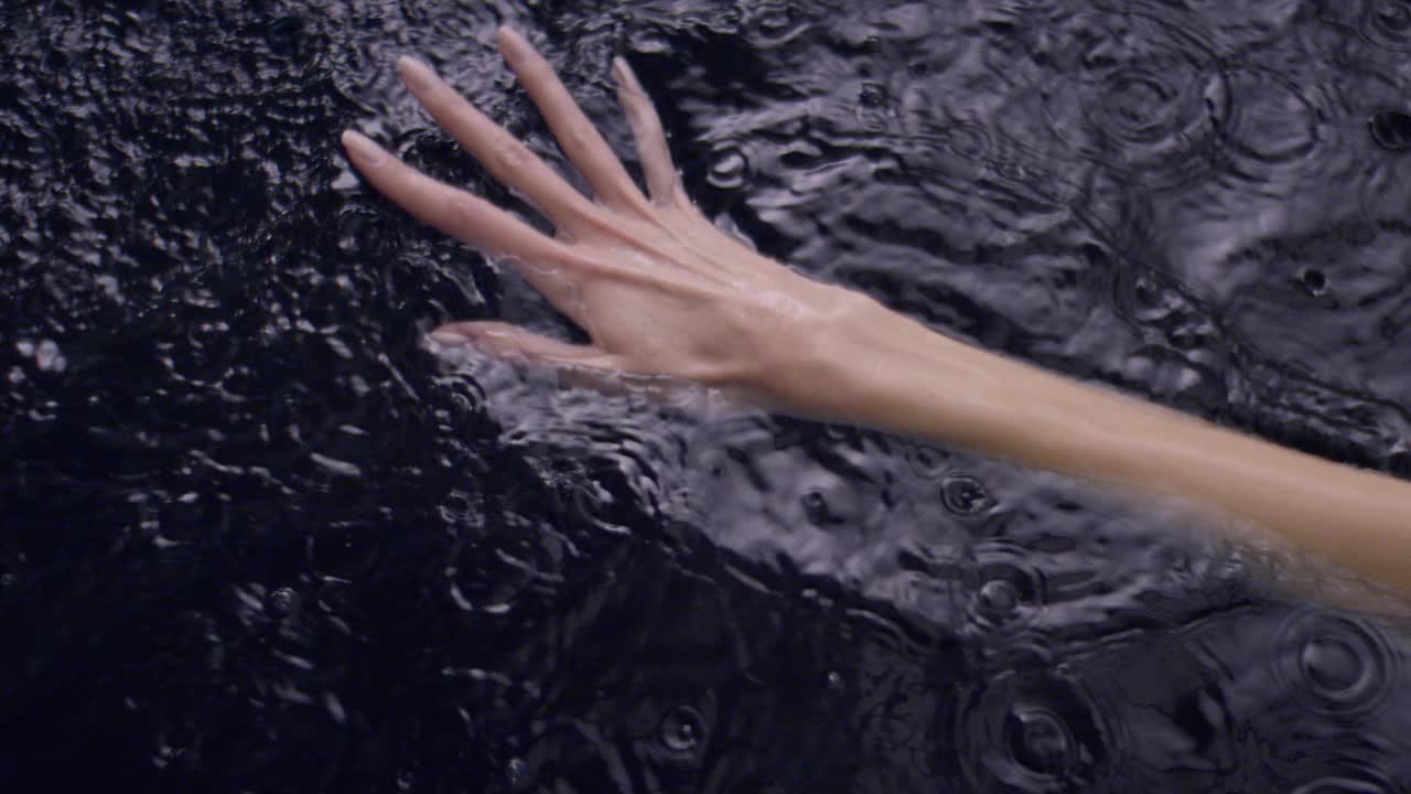 水面粗糙。女性用手轻轻泼洒并触摸液体视频下载