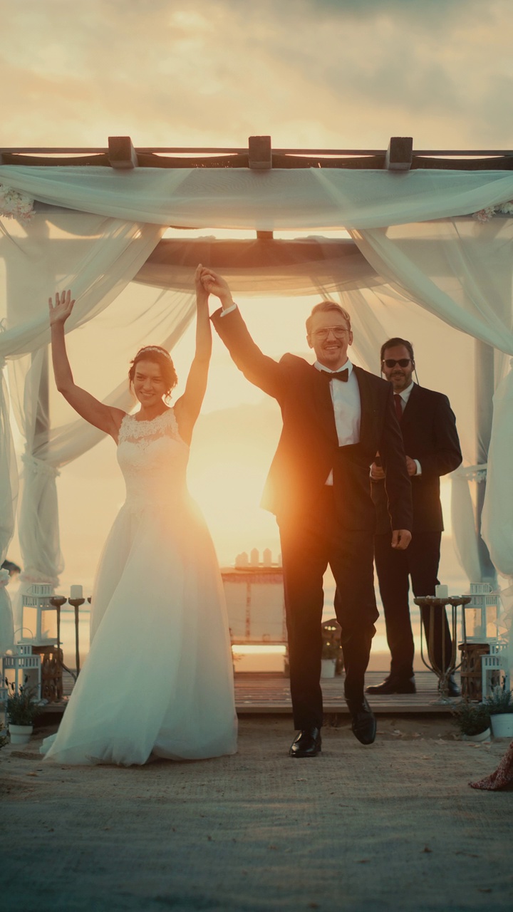 垂直画面:美丽的新娘和新郎在海边的户外婚礼上。多民族多元文化的浪漫情侣和好友的婚礼场所。视频下载