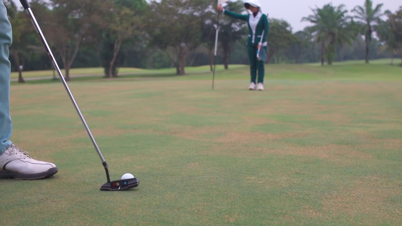 4K亚洲男子高尔夫球，高尔夫球在球道上通过一个洞视频素材