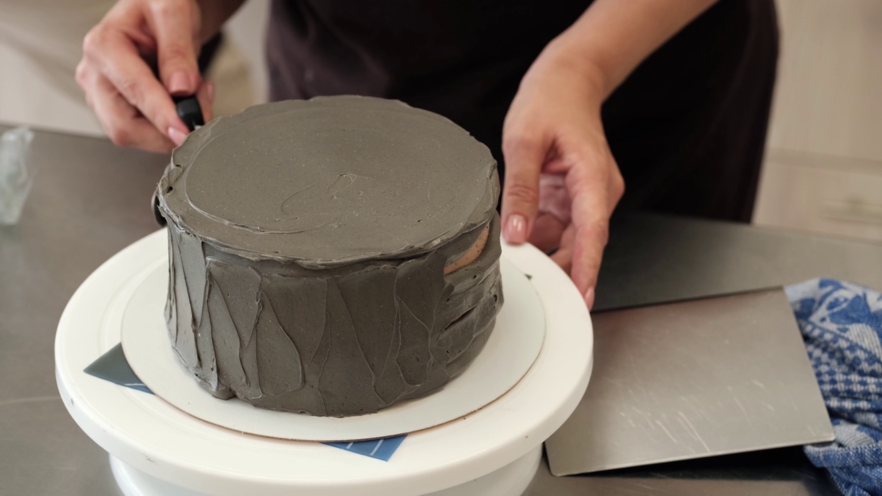 用灰色奶油奶酪装饰巧克力蛋糕的女人的特写镜头。缓慢的运动。蛋糕制作过程视频素材